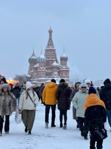 Moscow, Russia - December 16, 2023: Crowds of people on Red Square, enjoying snow, games and Christmas market. St. Basil Cathedral in snow