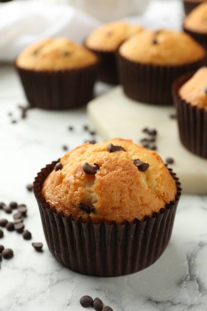 istock Delicious sweet muffin with chocolate chips on white marble table, closeup 1867633240