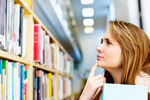 istock What shall I read today? Pretty woman choosing library books 186763725
