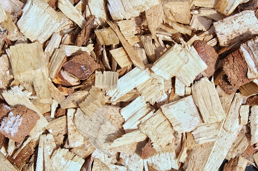 Pile of wood chips background. Texture of colored wood pieces. Natural bark material pattern. Decorative mulch