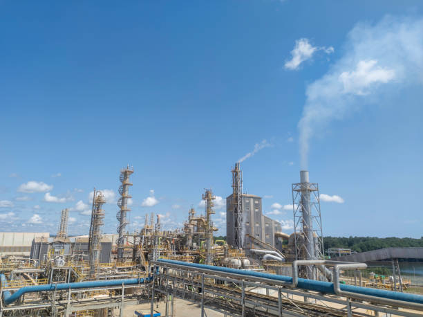 Fertilizer factory Fertilizer factory producing smoke in chimneys against the backdrop of a bright, cloudy blue sky ammonia fertilizer stock pictures, royalty-free photos & images