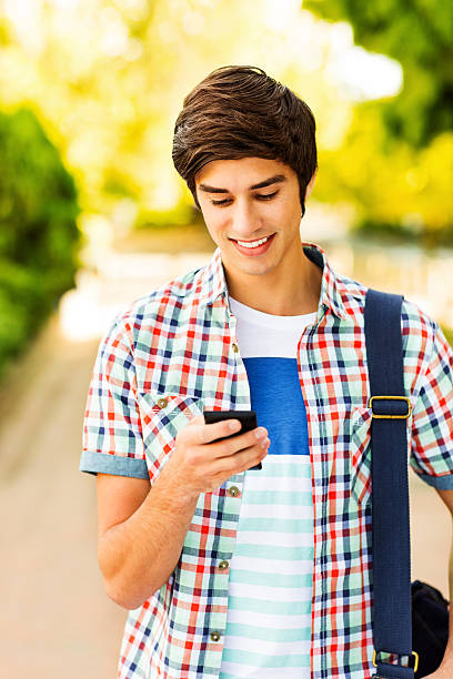 istock Male Student Reading Text Message On Smart Phone At Campus 186764586