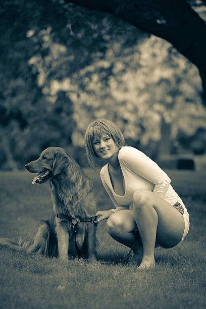 Young Caucasian woman with her pet dog on the grass lawn.