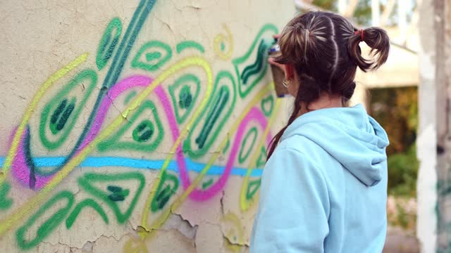 Young woman doing graffiti on the wall