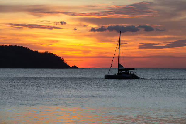 dramatyczny zachód słońca nad wodą z żaglówką - costa rican sunset zdjęcia i obrazy z banku zdjęć