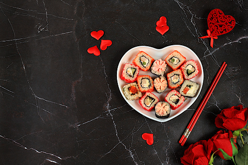 Valentine's Day food, Heart of fresh sushi rolls with roses, traditional Japanese cuisine, banner for advertising or invitation bar, menu, place for text, top view, selective focus