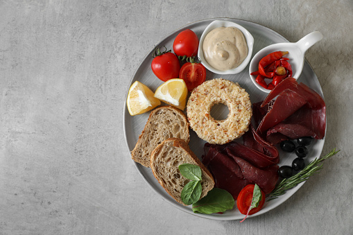 Delicious bresaola and other ingredients for sandwich on light table, top view. Space for text