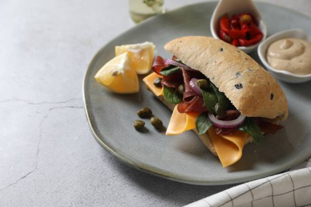 istock Delicious sandwich with bresaola, cheese and onion served on light grey table, space for text 1867666081
