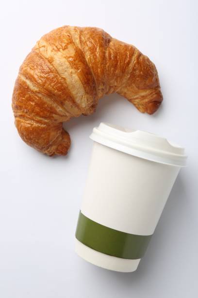 istock Delicious fresh croissant and paper cup with coffee on white background, flat lay 1867667689