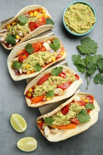istock Delicious tacos with guacamole, meat and vegetables served on grey table, flat lay 1867669314