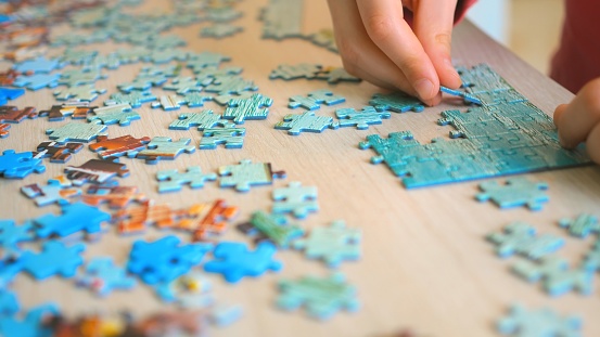 Young man engaged assembling puzzle, focused leisure. concentration enjoyment, puzzle tool mental stimulation young individual immersed piecing together, reflecting puzzle's appeal various age groups.