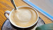 Hand stirs coffee foam spoon, health-conscious routine. mindful preparation coffee, health aspect enjoying lighter, foam-topped brew. health-aware choices daily life part healthy lifestyle commitment.