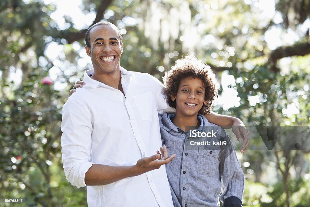 Brothers Young man (19 years) with little brother (9 years) standing in park.  Mixed race African American and Caucasian. African Ethnicity Stock Photo