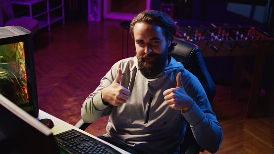 Man turning gaming chair around, greeting viewers before playing videogame tournaments online during stream. Friendly professional gamer saluting audience during livestream