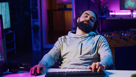 Streamer doing charitable marathon during live broadcast, struggling to remain awake while playing videogames. Gamer trying to not fall asleep doing livestream with viewers all day