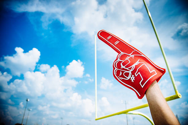 American Football Fan American Football Fan raising foam finger against field goal american football field photos stock pictures, royalty-free photos & images