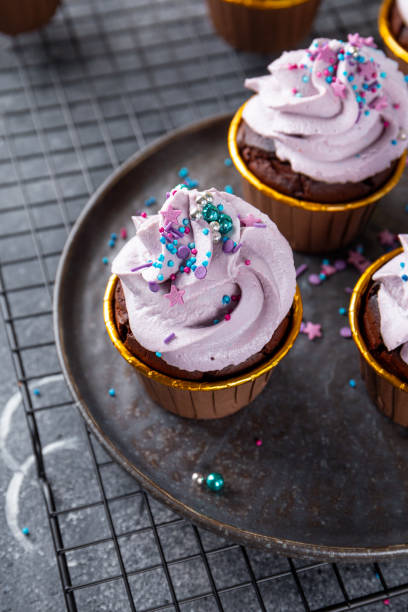 istock Festive chocolate cupcakes with lilac cream cheese on grey background copy space for text vertical photo 1867721872