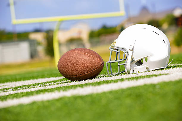 istock Sports:  Football and helmet on playing field. 186774602
