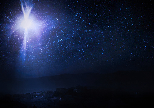 A conceptual photo montage.  The town is literally modern day Bethlehem, and the Christmas star is depicted in the night sky that tradition holds shone the evening that Jesus Christ was born. Horizontal image with copy space.
