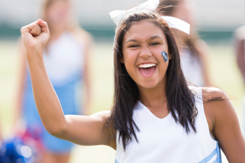 Excited cheerleader lifting a fist while cheering.