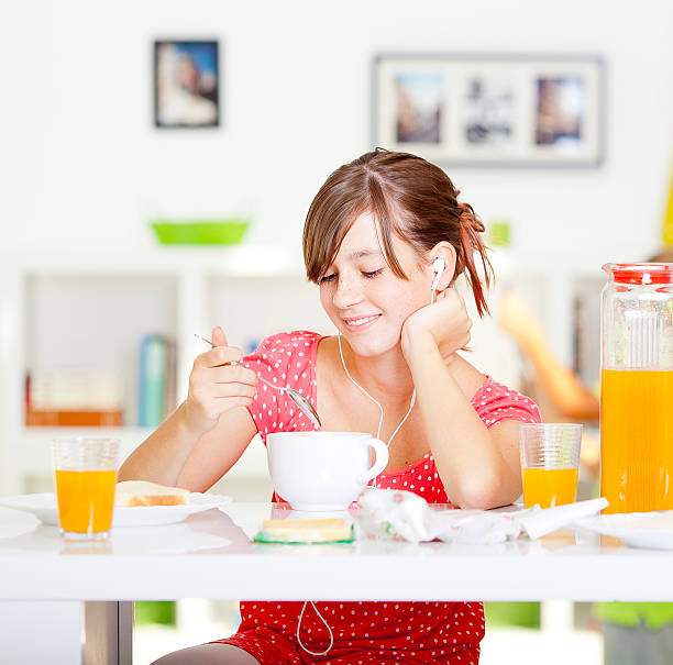 Teenage girl having breakfast and listening the music stock photo