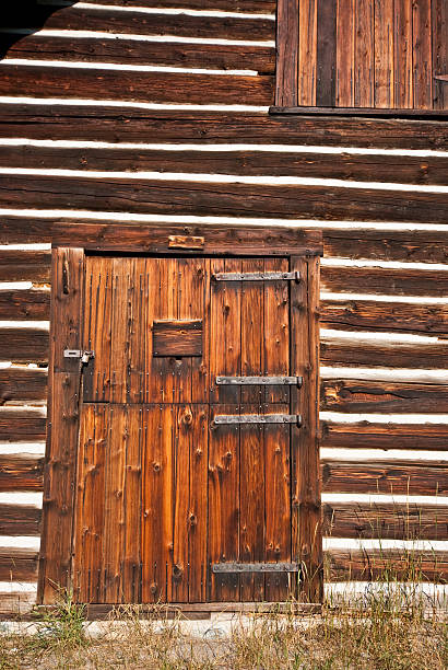 Front Door of Historic Lubec Barn (1926) The historic Lubec barn was originally built in 1926 at the Lubec Ranger Station about 7 miles south of East Glacier. In the summer of 1977, the barn was taken apart and moved as part of an historical restoration project. The disassembled barn was transported to and reassembled piece-by-piece at the Saint Mary Ranger Station in Glacier National Park, Montana, USA. jeff goulden mountain stock pictures, royalty-free photos & images