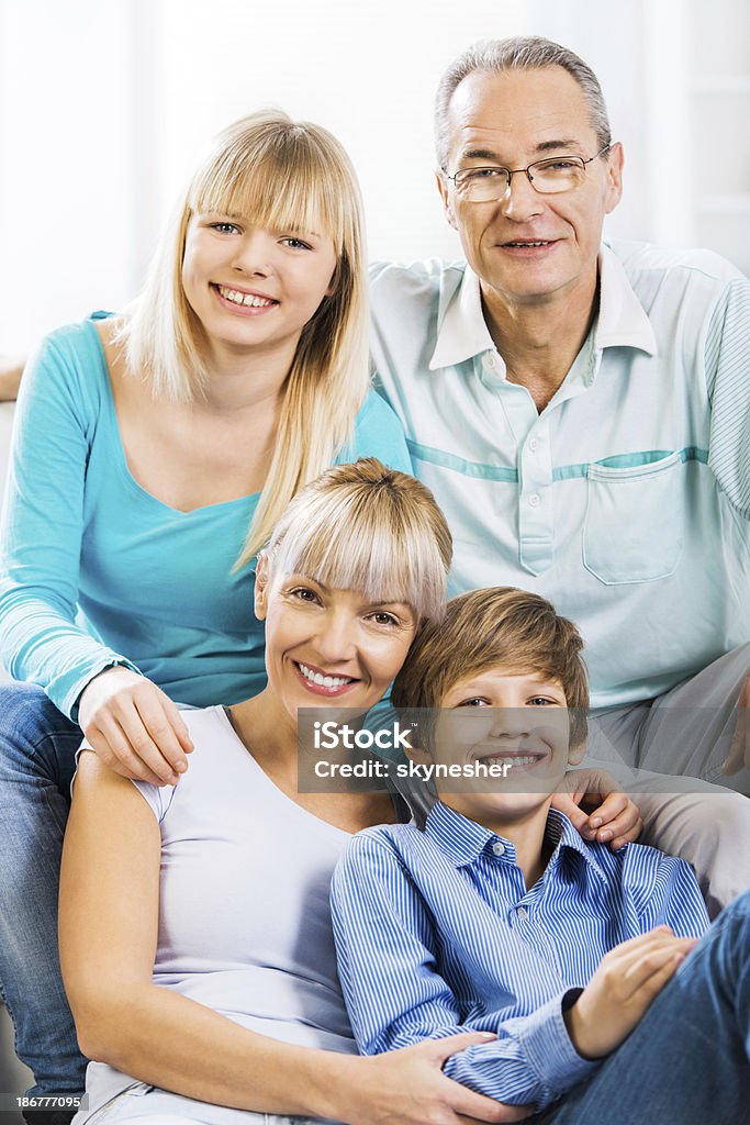 Embraced family at home. Happy embraced family at home looking at the camera.    Adolescence Stock Photo