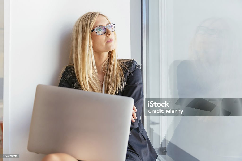 Executive z laptopa patrząc przez okno - Zbiór zdjęć royalty-free (Biznesmenka)