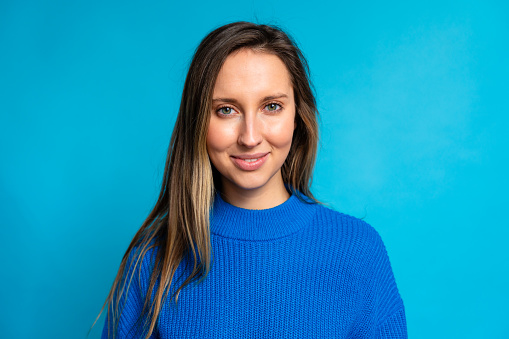 Portrait of a beautiful young woman in a blue sweater on a blue background