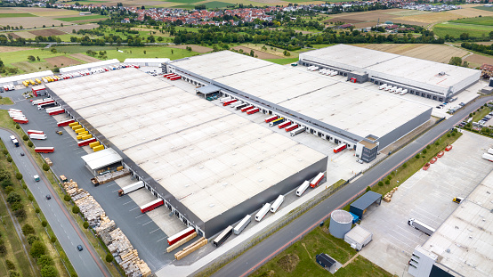 Loading bay, truck parking lot, unrecognisable industrial building, logistics - aerial view - tracking shot