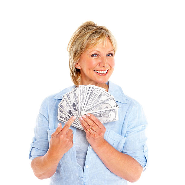 Smiling mature female showing money Portrait of a smiling mature female holding paper currency against white background one mature woman only stock pictures, royalty-free photos & images