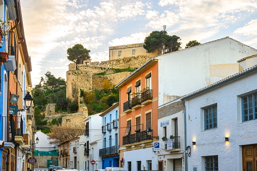 Denia, Alicante, Spain - Jan. 11, 2023: Architecture of houses contrasted against a fortified wall on top of a hill.