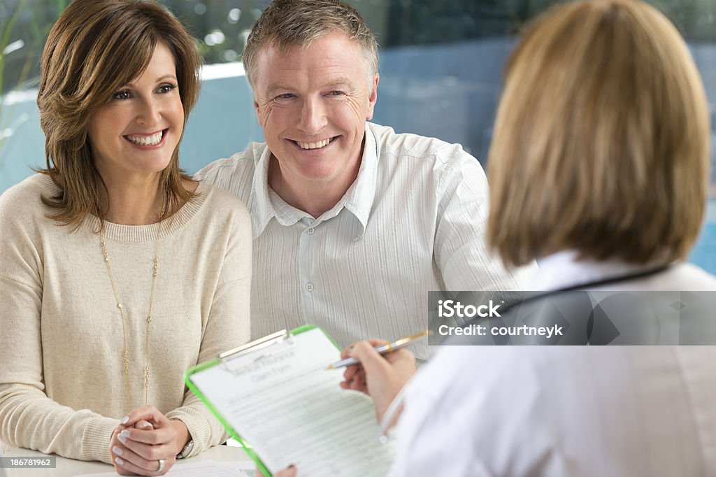 Doctor filling out insurance form with mature couple Doctor filling out insurance form with mature couple. Shallow focus Doctor Stock Photo