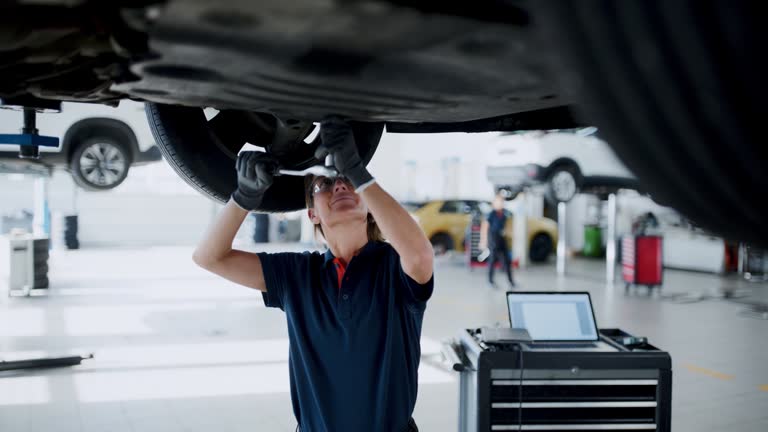 Female mechanic working under car in auto repair shop