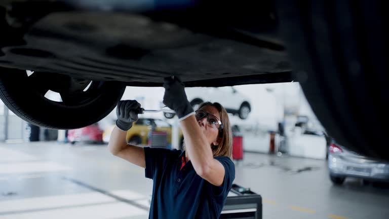 Female mechanic working underneath car in auto repair shop