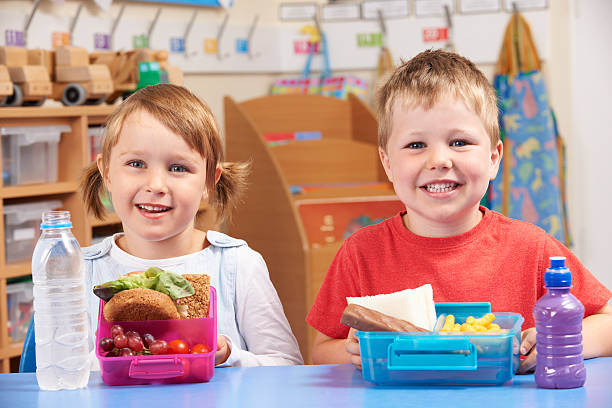 grundschule schüler mit gesunden und ungesunden lunchbox - lunch box child school lunch stock-fotos und bilder