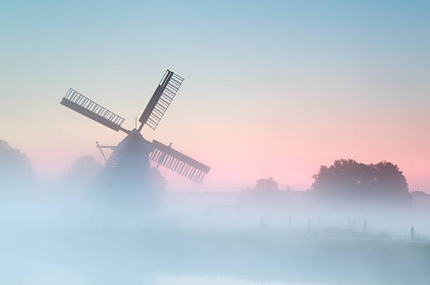 istock charming Dutch windmill in dense sunrise fog 186785518