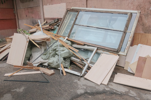 Furniture thrown into the trash, garbage in bags and old windows with broken glass