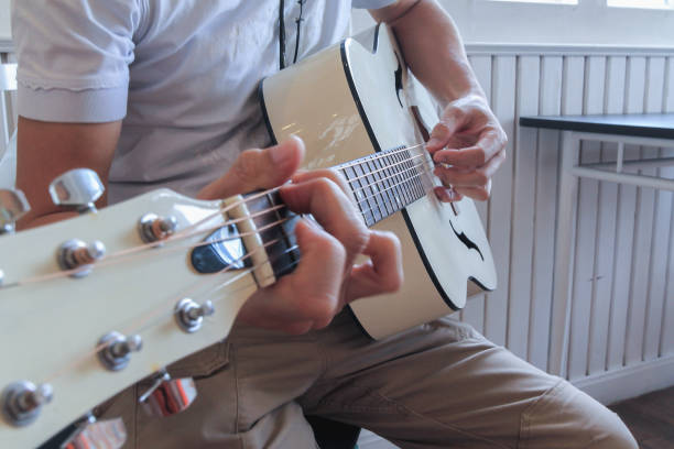 istock A young man is practicing playing guitar in a music practice room before performing in order to reduce the mistake of playing guitar on stage. Close Up Young man is holding guitar chords for practice. 1867884432