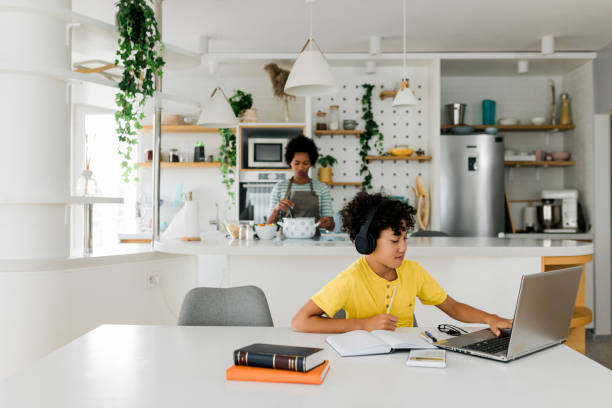 istock Boy doing homework while his mother cooking in the background 1867909441