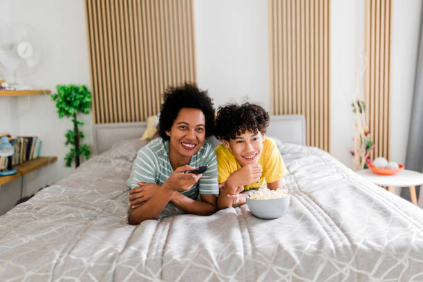 istock Mother and son watching TV and lying on bed 1867912639