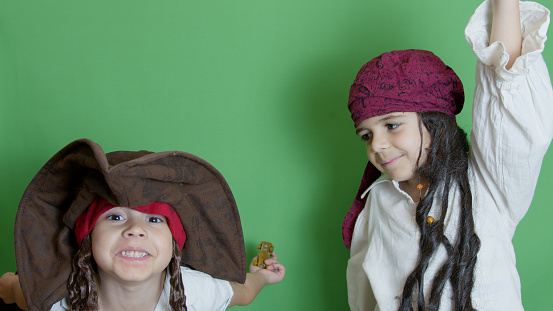 Cute cids in pirate costumes playing on the green background
