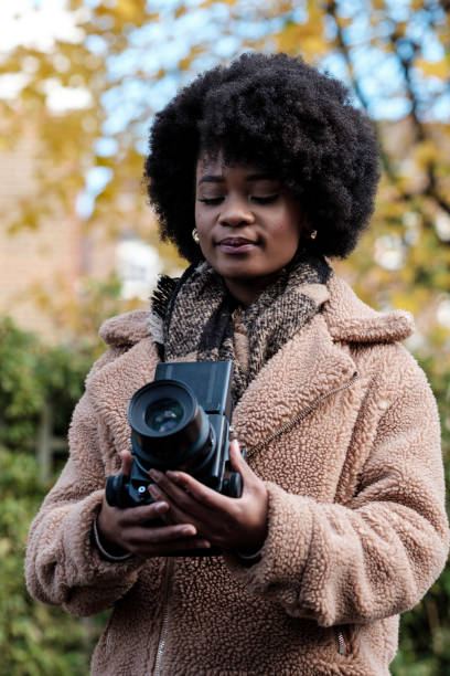 istock Curly black woman enjoying his photography hobby using analog camera. 1867921560