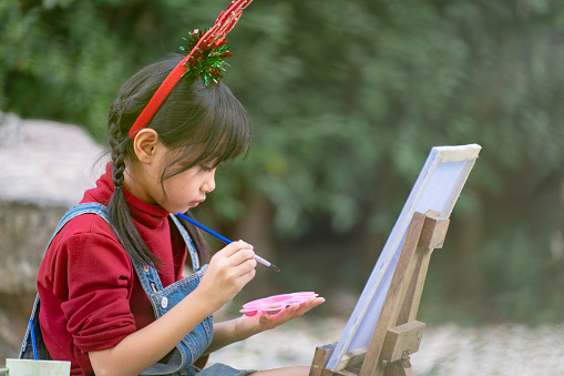 A little girl is happy to join the Christmas day.and is drawing and coloring.