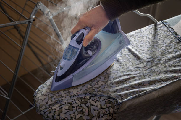 istock Ironing laundry with a light purple colored hot steam iron on the ironing table 1867932063