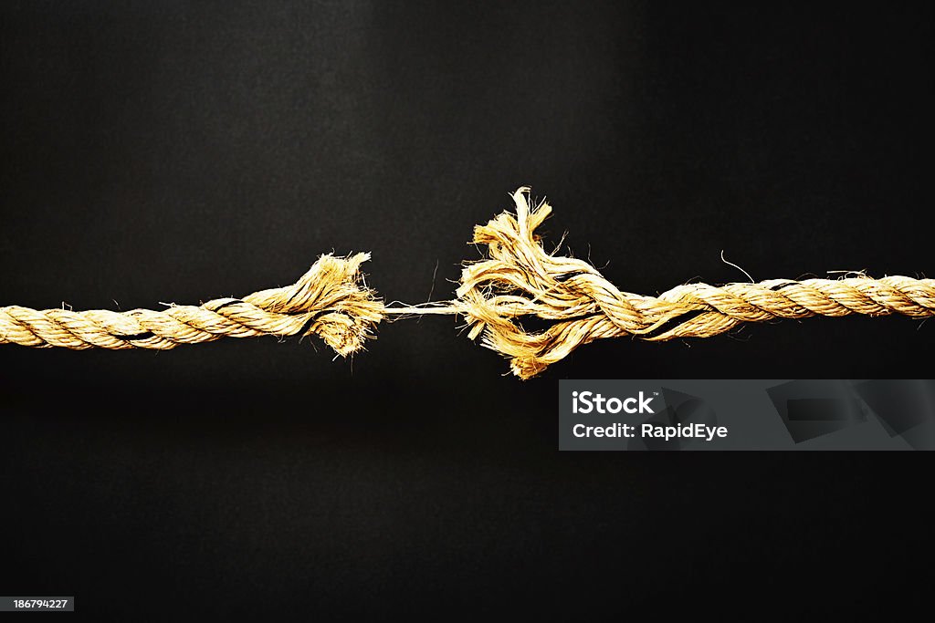 Extreme stress symbolized by rope frayed to final strand Symbolic of extreme stress, this rope is frayed to its very last strand! Temper tantrums and nervous breakdowns are sure to happen soon. Black background with copy space. Breaking Stock Photo