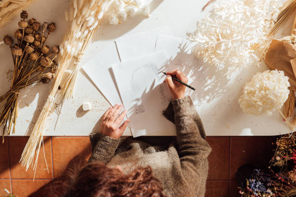istock Unrecognizable artist painting on sheet at table with dried plants 1867968886