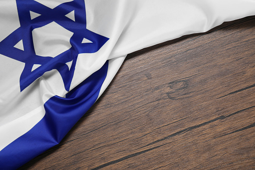 Flag of Israel on wooden background, above view and space for text. National symbol