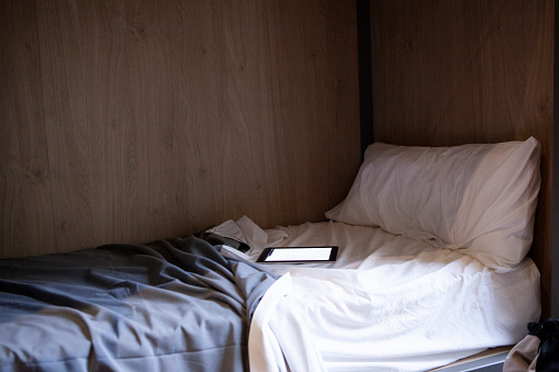 Digital tablet turned on lying on messy hostel bed