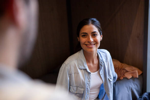 istock Smiling adult woman sitting on hostel bed while talking with room mate 1867984631